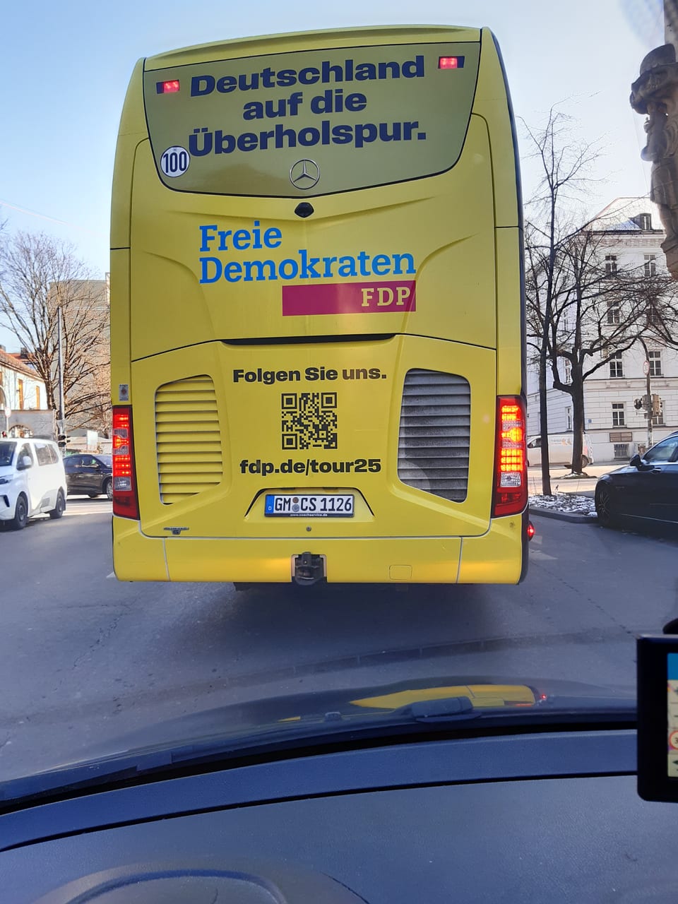 Rückansicht des gelben FDP-Wahlkampfbusses mit dem Schriftzug „Deutschland auf die Überholspur.“ und „Freie Demokraten FDP“ auf einer Straße