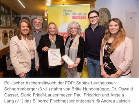 Sechs Personen stehen nebeneinander vor einem gelben FDP-Roll-up-Banner, in der Mitte hält Sabine Leutheusser-Schnarrenberger die Urkunde „Das Silberne Fischmesser 2025“, daneben wird das Fischmesser in einer Schachtel präsentiert