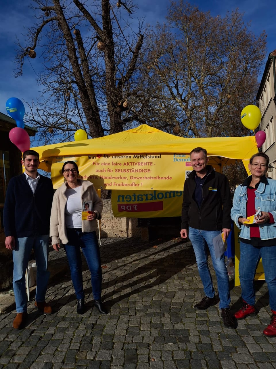 Vier Mitglieder des Kreisverbands vor dem gelben Zelt mit dem Banner für eine faire Aktivrente, auch für Selbständige wie Landwirte, Handwerker, Gewerbetreibende und Freiberufler