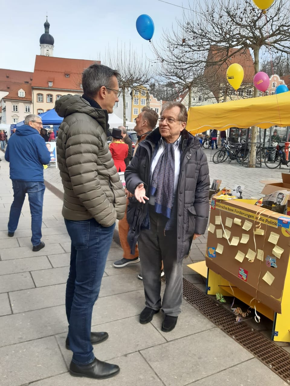 Norbert Eisenberg (rechts) im Gespräch mit einem Besucher am FDP-Stand, dahinter eine Stellwand mit Wünschen und Forderungen an die Politik und die Landsberger Altstadt