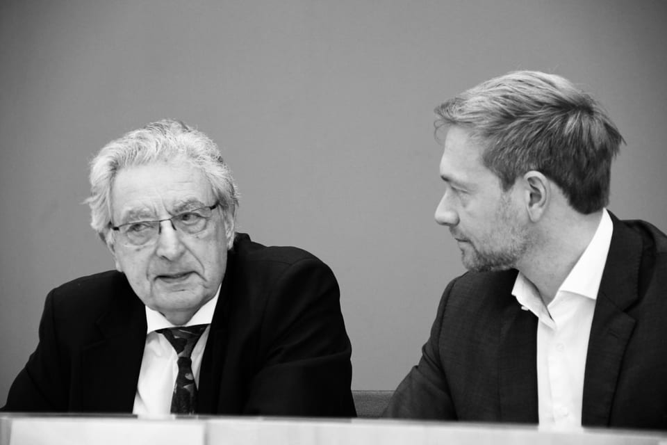 Schwarz-Weiß-Aufnahme von Gerhart Baum (links) und Christian Lindner (rechts), die an einem Tisch nebeneinandersitzen