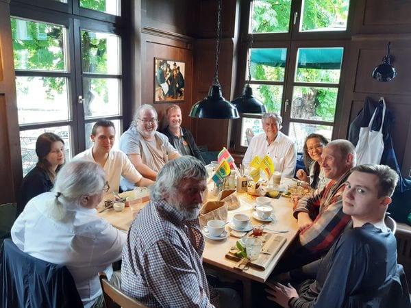 Gäste des Politischen Frühstücks an einem Tisch in einer holzgetäfelten Gaststube, auf dem Tisch Kaffeetassen und FDP-Fähnchen