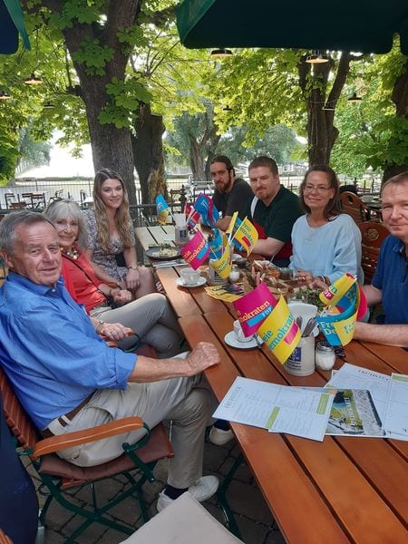 Größere Gruppe an einer langen Biergartentafel mit FDP-Tischfähnchen an einem Sommertag