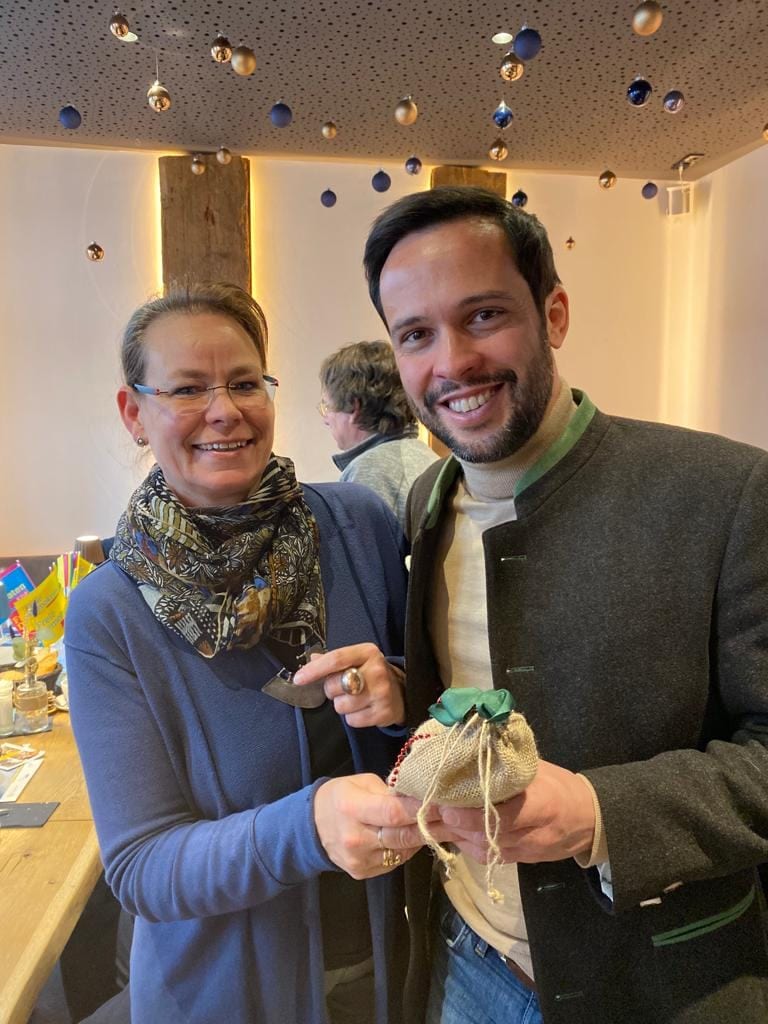 Zwei Gäste halten lächelnd ein kleines Jutesäckchen als Geschenk in die Kamera